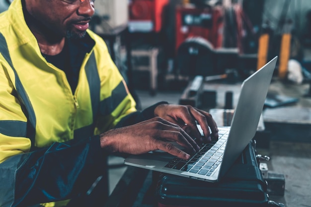 Factory worker working with laptop computer to do adept procedure checklist