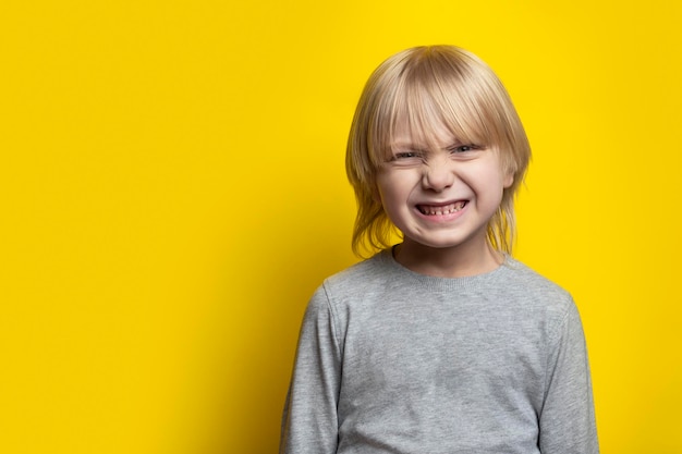 Fairhaired boy make face Portrait of blond boy on yellow background Copy space