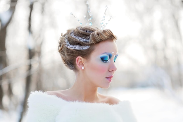 Fairytale cosplay of ice queen Portrait of woman in the dress posing in the snowy forest