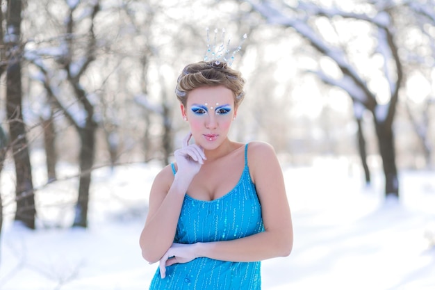 Fairytale cosplay of ice queen Woman in the dress posing in the snowy forest