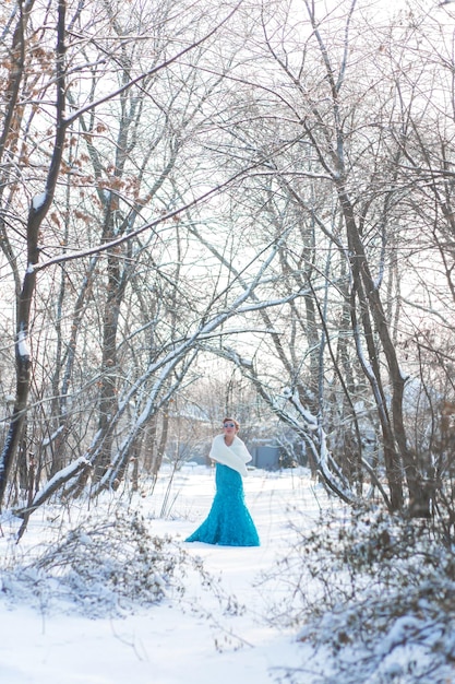 Fairytale cosplay on snow queen Woman in the dress posing in the snowy forest