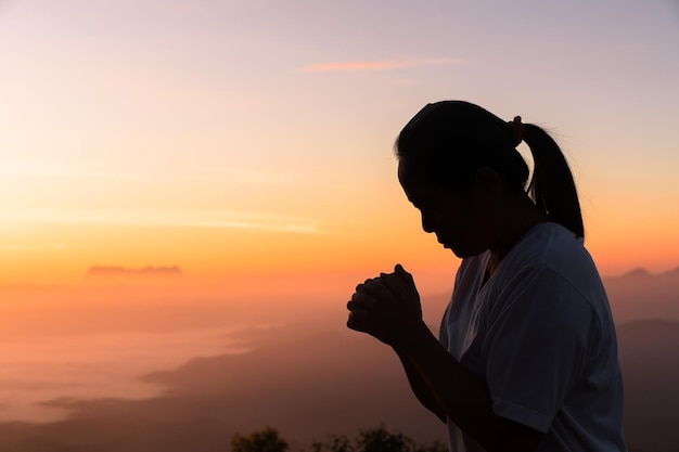 Faith of christian concept Spiritual prayer hands over sunshine with blurred beautiful sunrise or sunset background Christians who have believe faith in God morning prayer