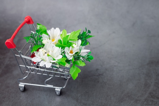 A fake bunch of flowers in a mimi shopping cart