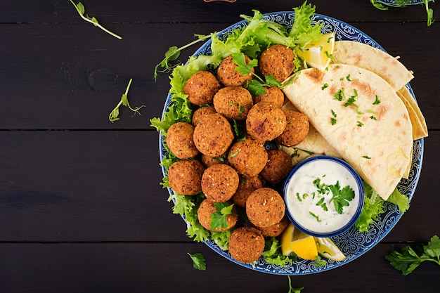 Falafel, hummus and pita. Middle eastern or arabic dishes on a dark table Halal food. Top view. Copy space