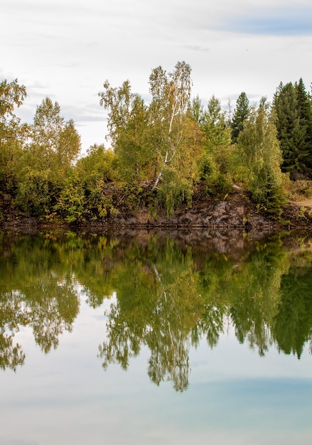 fall foliage reflected on a lake with a glass like mirror water surface.