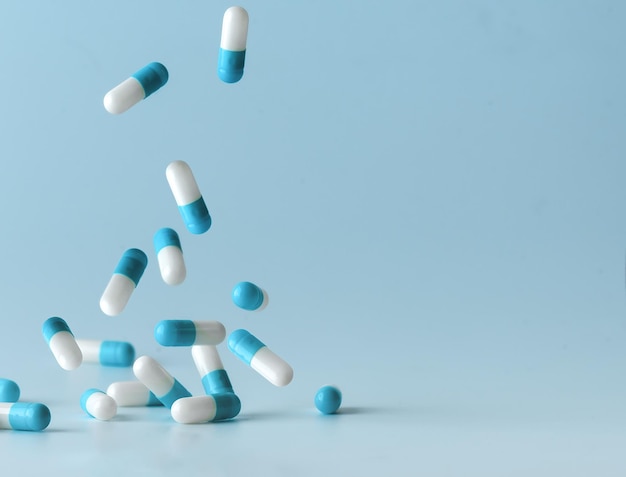 Falling blue white capsules on blue background