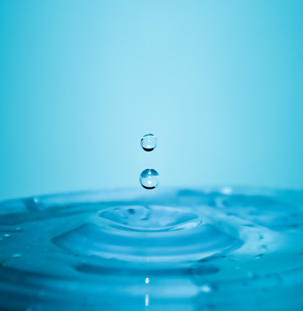 Falling drops of pure blue water in macro