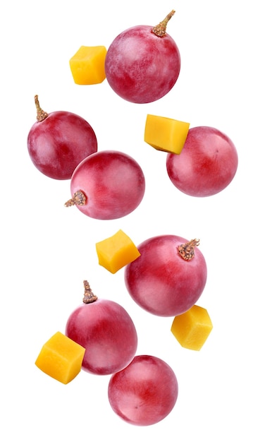 Falling grapes and mango isolated on a white background. whole berries and cubes of pulp in the air.