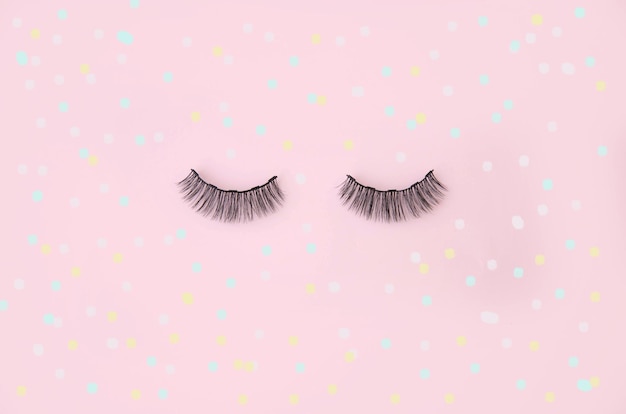 False eyelashes on a pink polka dot background place for text template blank