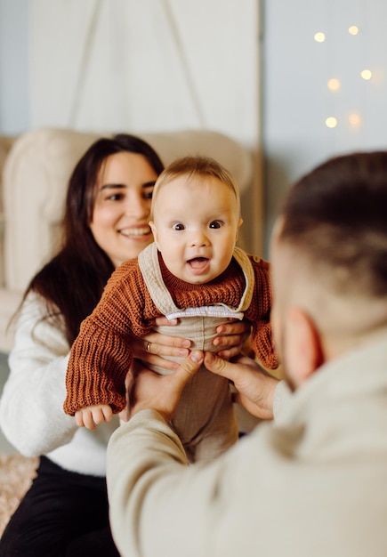 Families Portrait Of Happy Young Mother And Father with Child Posing In home Interior