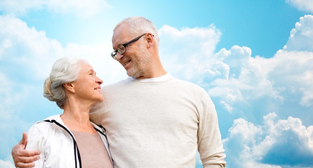 family, age, love, relations and people concept - happy senior couple over blue sky and clouds background