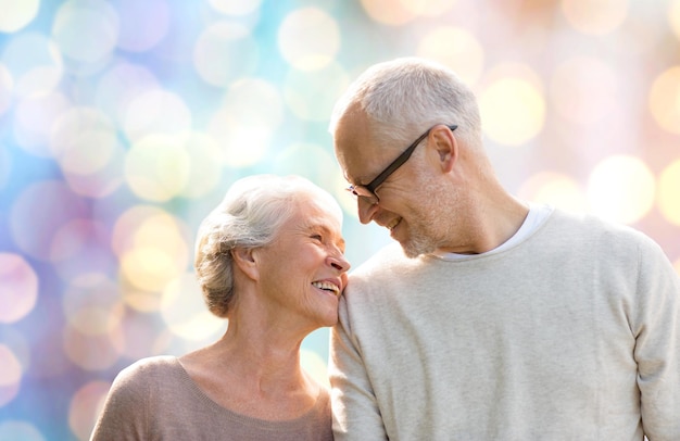 family, age, love, relations and people concept - happy senior couple over holidays lights background