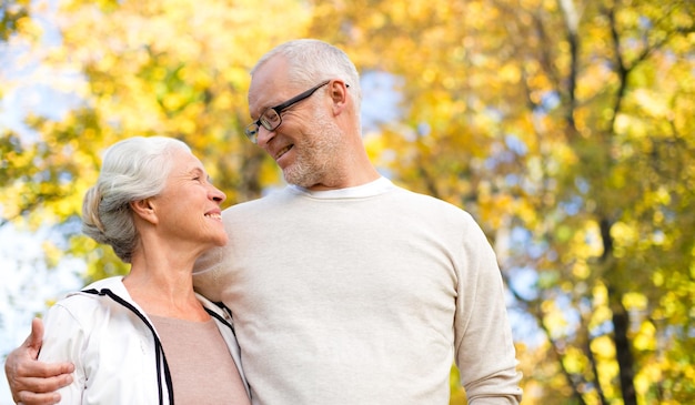 family, age, season and people concept - happy senior couple over autumn trees background