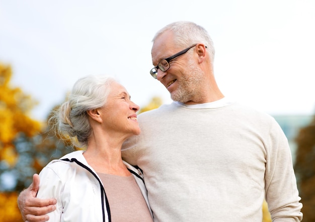 family, age, tourism, travel and people concept - senior couple hugging in city park