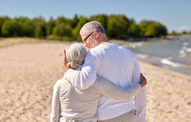 family, age, travel, tourism and people concept - happy senior couple hugging on summer beach