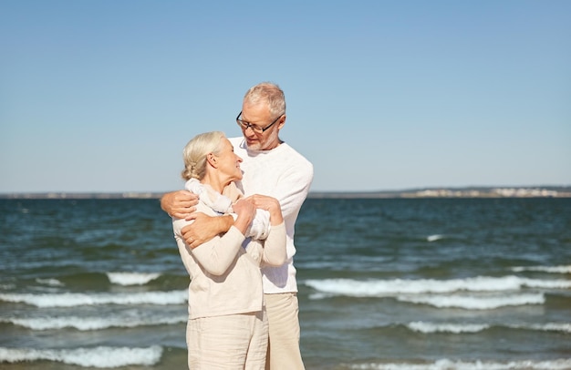 family, age, travel, tourism and people concept - happy senior couple hugging on summer beach