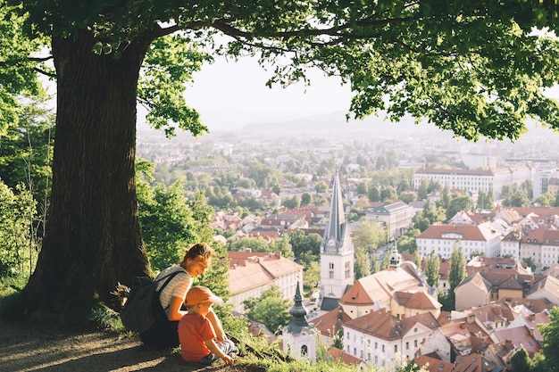 Family on background of Ljubljana Slovenia Europe Woman with her child boy look at panorama of european city from the hill Mother and kid outdoors at spring or summer time