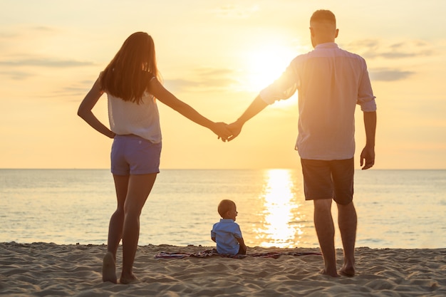 Family on the beach concept, Caucasian boy siting and holding sand on the tropical beach in sunset time 