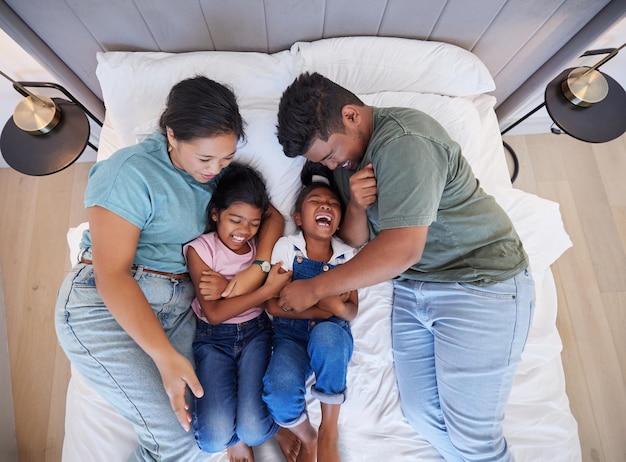 Family bed home relax and parents in bedroom with children care for comic kids and love in house together from above Top view of girl siblings laughing with happy mother and father in the morning