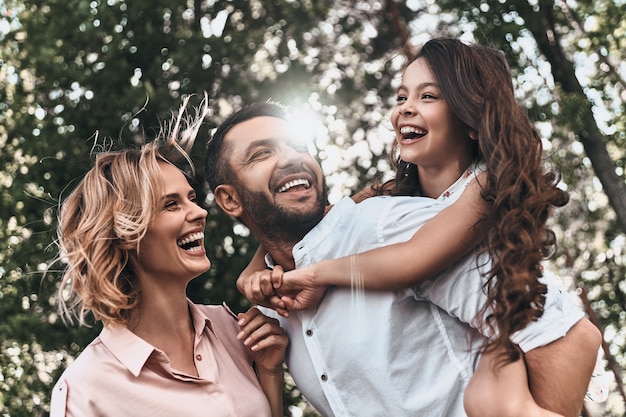 Family bonds. Happy young family of three smiling while spending free time outdoors