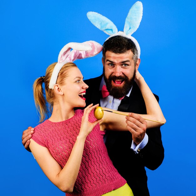 Family celebrating easter bunny couple in rabbit ears painting egg for holidays