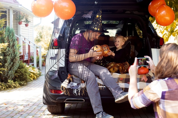 Family celebrating halloween car trunk having fun together autumn