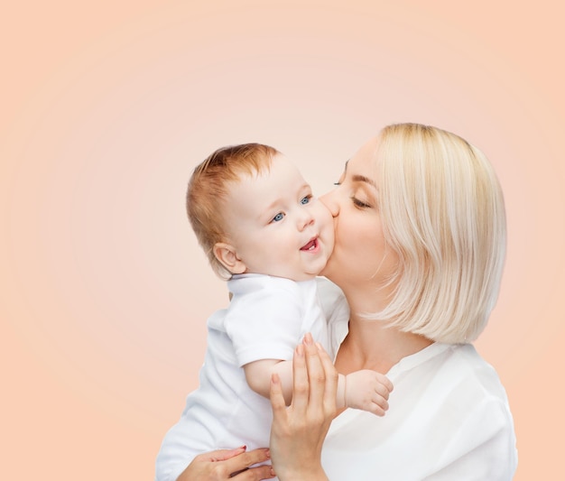 family, child and parenthood concept - happy mother kissing smiling baby