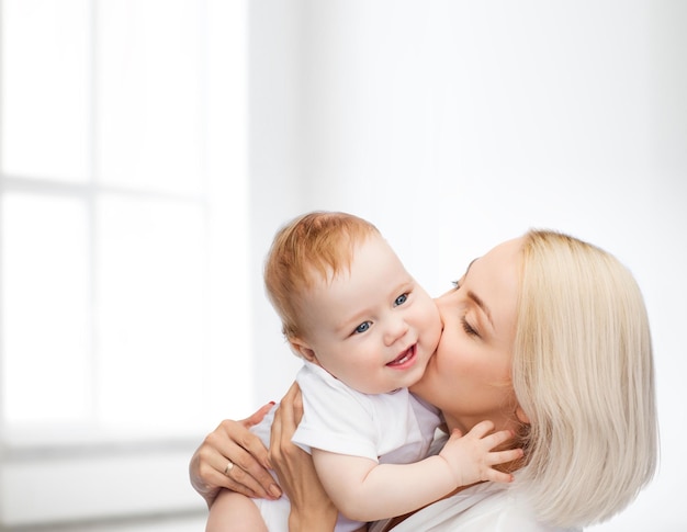 family, child and parenthood concept - happy mother kissing smiling baby