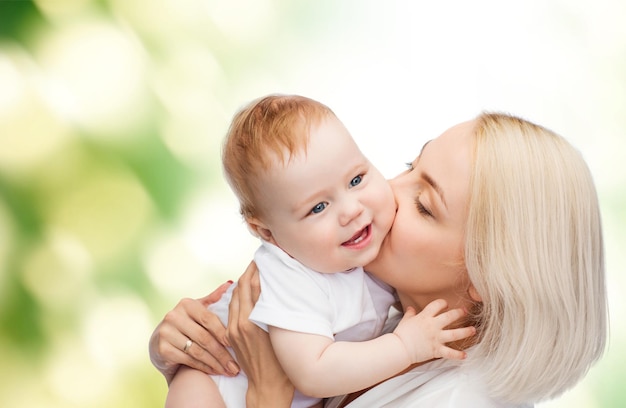 family, child and parenthood concept - happy mother kissing smiling baby