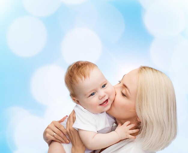 family, child and parenthood concept - happy mother kissing smiling baby