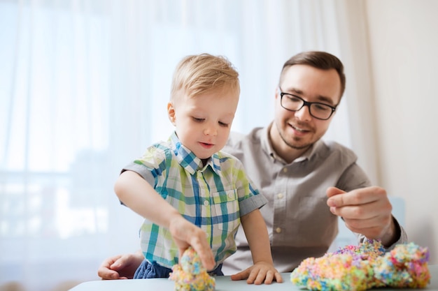 family, childhood, creativity, activity and people concept - happy father and little son playing with ball clay at home