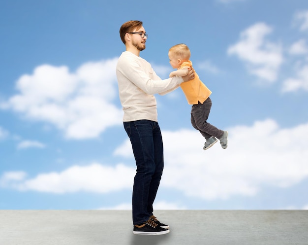 Photo family, childhood, fatherhood, leisure and people concept - happy father and little son playing and having fun over blue sky and clouds background