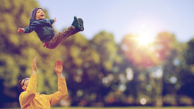 family, childhood, fatherhood, leisure and people concept - happy father and little son playing and having fun outdoors over summer park background