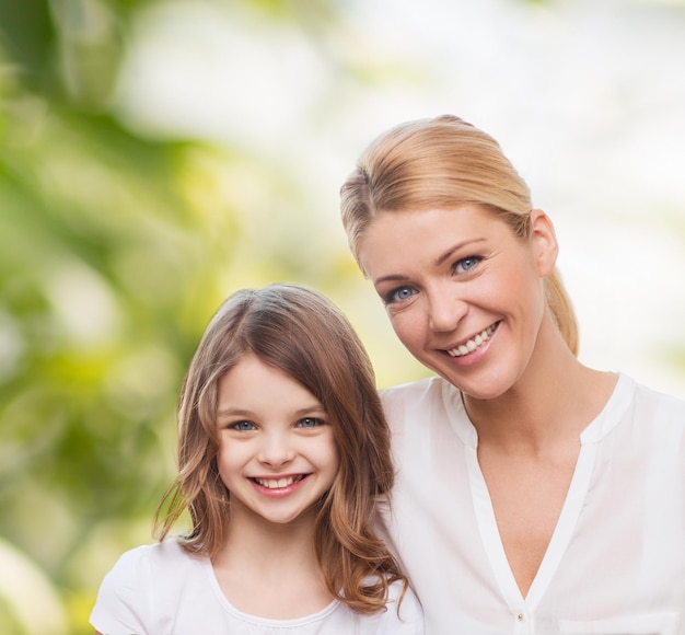 family, childhood, happiness, ecology and people - smiling mother and little girl over green background