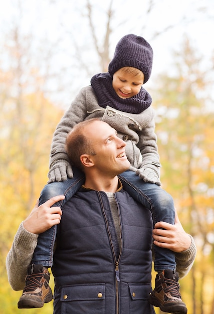 family, childhood, season and people concept - happy father and son having fun in autumn park