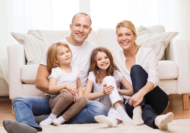 family, children and home concept - smiling family with and two little girls sitting on floor at home