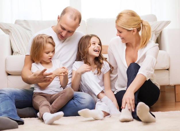 family, children and home concept - smiling family with and two little girls sitting on floor at home