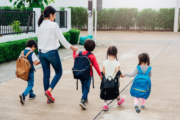 Family children kid son girl and boy kindergarten walking going to school holding hand with mother mom