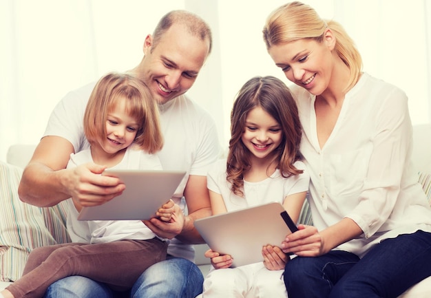 Photo family, children, technology, money and home concept - smiling family and two little girls with tablet pc computers at home