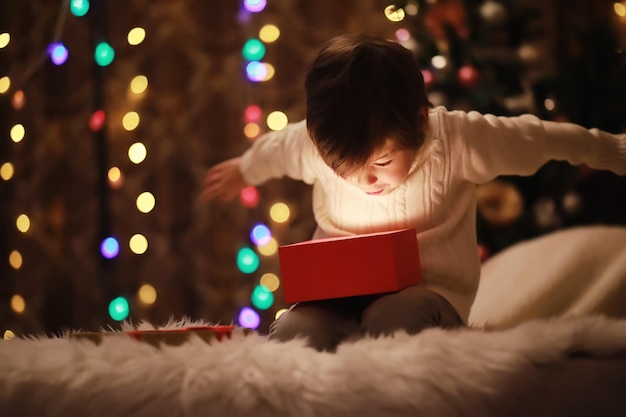 Family on Christmas eve at fireplace Kids opening Xmas presents Children under Christmas tree with gift boxes Decorated living room with traditional fire place Cozy warm winter evening at home