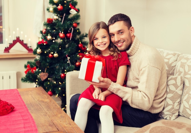 family, christmas, x-mas, winter, happiness and people concept - smiling father and daughter holding gift box