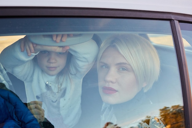 Family concept Portrait of mother and daughter through the glass of a car