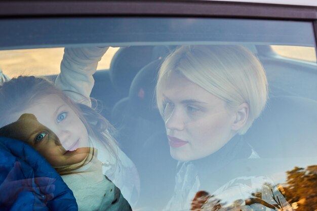 Family concept Portrait of mother and daughter through the glass of a car