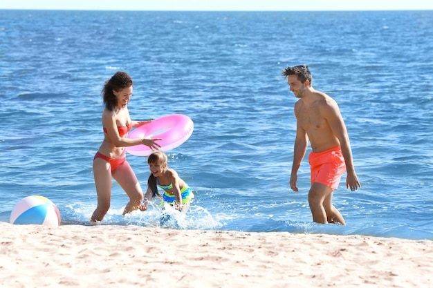 Family concept Young woman man and little girl playing on the sea shore