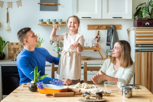 Family cooks at home mom dad and daughter knead the dough in a kitchen man girl woman together