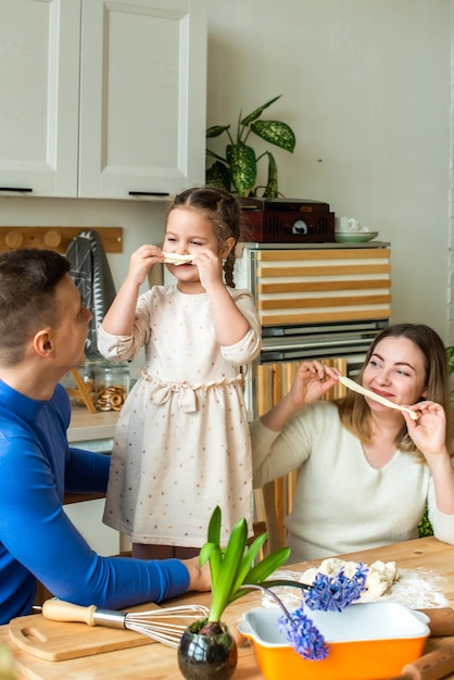 Family cooks at home mom dad and daughter knead the dough in a kitchen man girl woman together