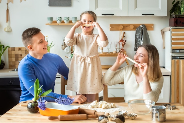 Family cooks at home mom dad and daughter knead the dough in a kitchen man girl woman together