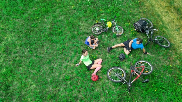 Family cycling on bikes outdoors aerial view from above, happy active parents with child have fun and relax on grass, family sport and fitness on weekend