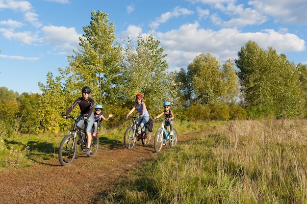 Family cycling outdoors. Happy parents with two kids on bikes