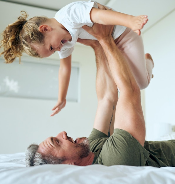 Family dad and lifting daughter on bed while having fun and enjoying time together bonding during airplane game family activity Playing support and laughing man and girl child in bedroom at home